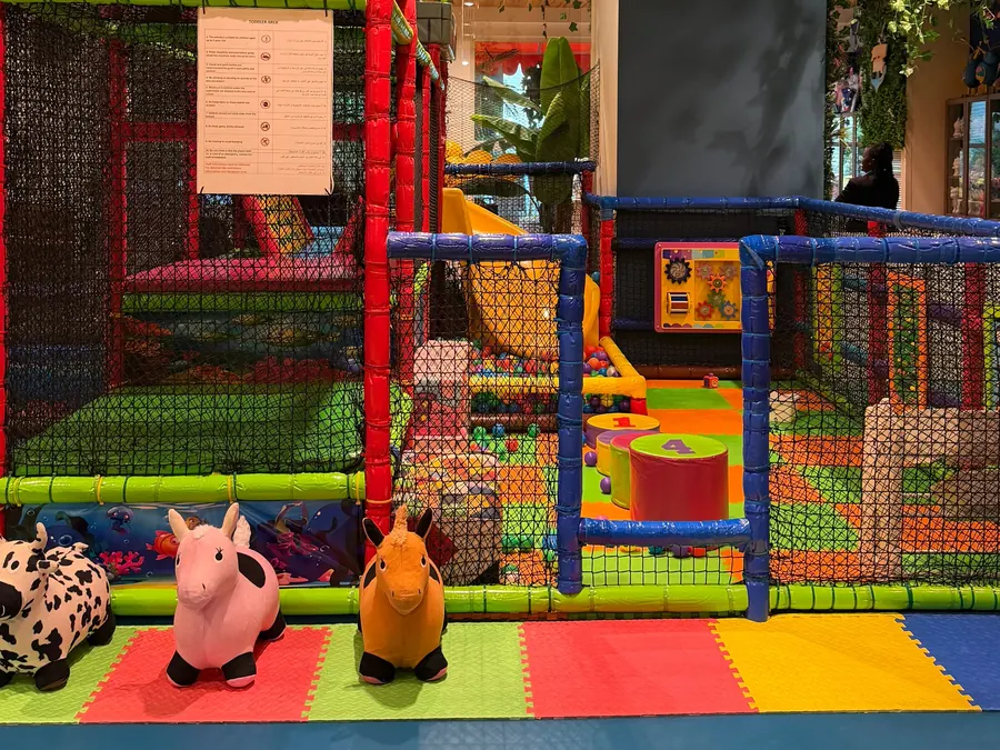 The gated toddler area with soft blocks and ride-on animals